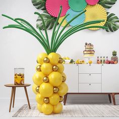 a large pineapple balloon sitting on top of a table next to a vase filled with flowers