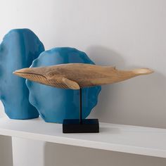 two blue sculptures sitting on top of a white shelf in front of a white wall