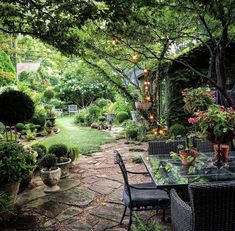 an outdoor dining area in the middle of a garden with lots of plants and flowers