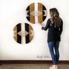 a woman is standing in front of two wall hangings that have arrows on them