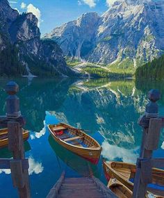 two boats docked at the end of a pier in front of some mountains and water