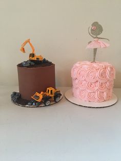 two cakes decorated with pink frosting and construction vehicles on top of each cake stand