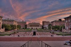 people are sitting on the steps in front of some buildings at sunset or sunrise time