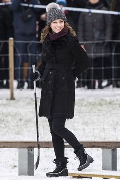 a woman standing in the snow with her skis