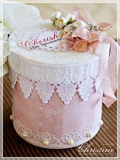 a pink and white hat box with lace on the top, flowers in the background