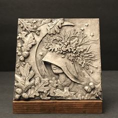 a metal plaque with an image of a woman's head and flowers on it