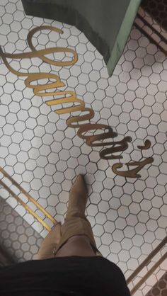 a person standing on a tiled floor next to a metal sign with the word goodbye