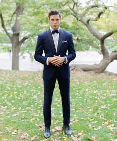 a man in a tuxedo poses for the camera with his hands on his hips