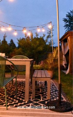 an outdoor patio with string lights strung over the table and chairs, along with potted plants