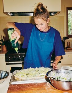 a woman in blue shirt and apron preparing food