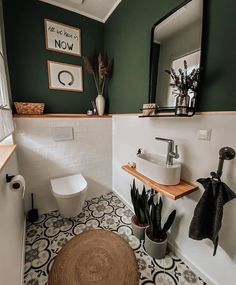 a bathroom with green walls and black and white flooring, including a round rug