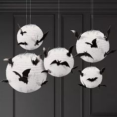 bats hanging from the ceiling in front of a black door with white paper lanterns on it