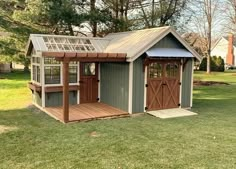 a small shed with a roof and windows on the side, sitting in a yard