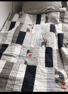 an unmade bed with blue and white quilts