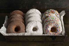 four donuts in a box with sprinkles and white frosting on them