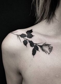 a black and white photo of a woman's back shoulder with leaves on it