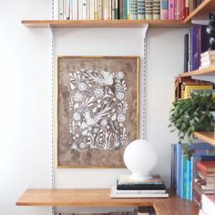 a book shelf with books and a painting on it's wall next to a vase