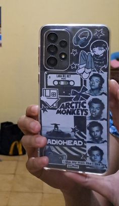 someone is holding up their phone case with stickers on it and there are other things in the background