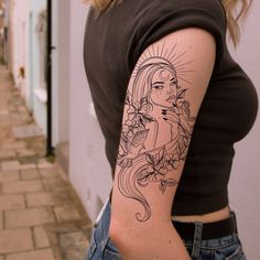 a woman's arm with a tattoo on it and flowers in her hair, next to a building