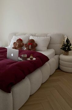 a laptop computer sitting on top of a bed next to a teddy bear and christmas tree