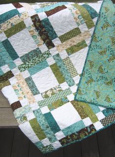 a green and white quilt sitting on top of a wooden bench