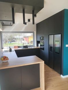 a modern kitchen with black cabinets and wood flooring is pictured in this image, there are fruit on the counter