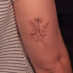 a woman's arm with a small flower tattoo on the left side of her arm