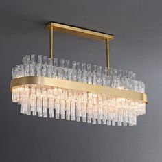 a chandelier hanging from the ceiling with clear glass tubes and gold metal frame