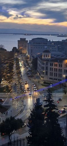 an aerial view of a city at night with lights on the street and water in the background