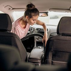 a woman sitting in the back seat of a car with her hand on the steering wheel