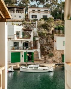 a boat is docked in the water next to some white buildings and green shutters