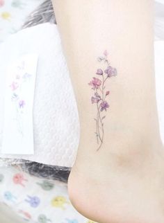 a small flower tattoo on the ankle that is sitting on a woman's foot