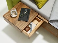 a wooden table with a book, glass and pen on it next to a couch