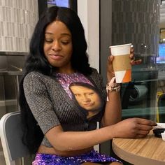 a woman sitting at a table holding a coffee cup