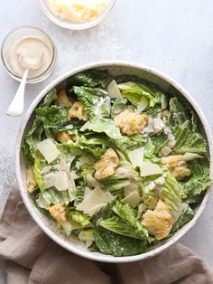 a salad with lettuce, cheese and dressing in a bowl on a table