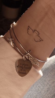 a woman's arm with a heart shaped charm and a quote on the wrist