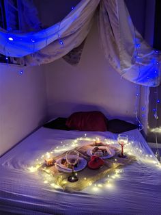 a bed that has some food on top of it with lights around the bedspread