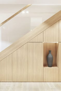 a vase sitting in the corner of a wooden shelf next to an open staircase case