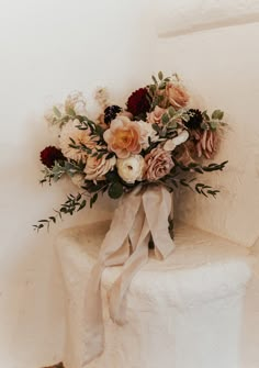 a bouquet of flowers sitting on top of a white chair with a ribbon tied around it