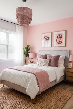 a bedroom with pink walls and white bedding in the center, two paintings on the wall