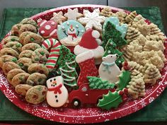 a platter filled with christmas cookies and decorated cookies on top of a red plate