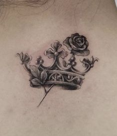 a woman's back with a crown and rose tattoo on her shoulder, which is also in black ink