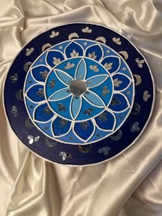 a blue and white plate sitting on top of a satin covered table cloth with an intricate design