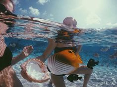 two people are swimming in the ocean and one person is holding a coconut under water