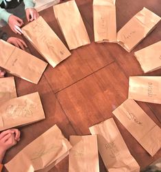 a group of children sitting around a wooden table with paper bags on top of it