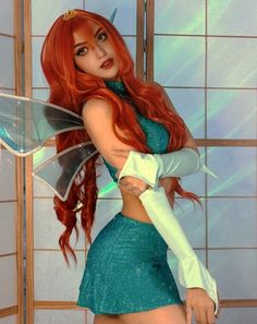 a woman dressed as a fairy with long red hair wearing a green dress and holding a knife