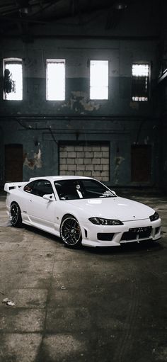 a white sports car parked in an old warehouse with no one on the front seat