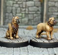 two small figurines of dogs sitting on top of each other in front of a stone wall