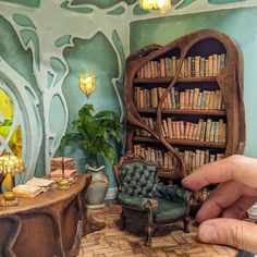 a hand is pointing at a miniature library