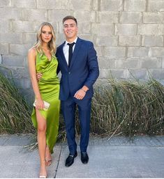 a man in a suit and woman in a green dress standing next to each other